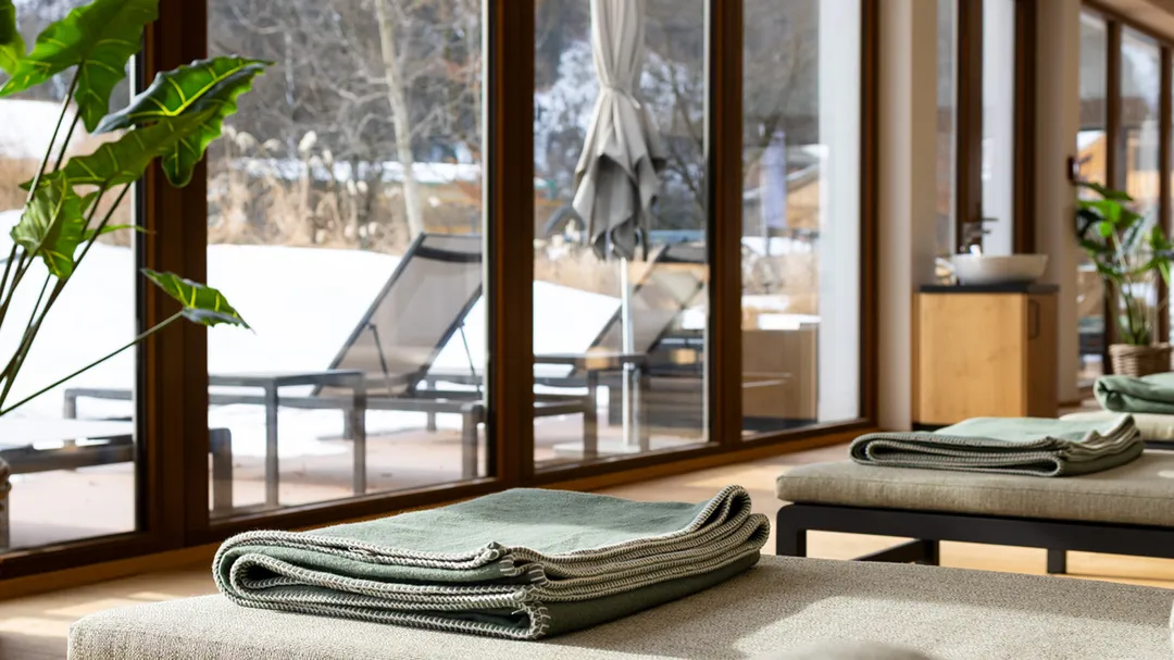 Liegen mit gefalteten Decken im Spa-Bereich mit Blick auf verschneite Terrasse
