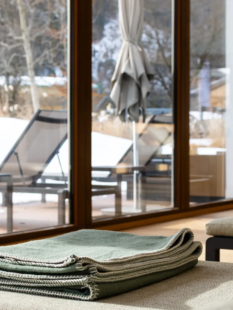 Liegen mit gefalteten Decken im Spa-Bereich mit Blick auf verschneite Terrasse