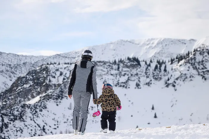 Mutter und Kind in Skibekleidung wandern durch verschneite Berglandschaft
