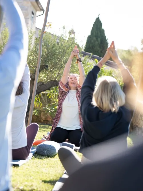 Gruppe bei Yoga-Übung im Freien mit erhobenen Armen im Garten