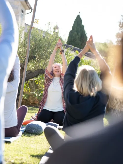 Gruppe bei Yoga-Übung im Freien mit erhobenen Armen im Garten