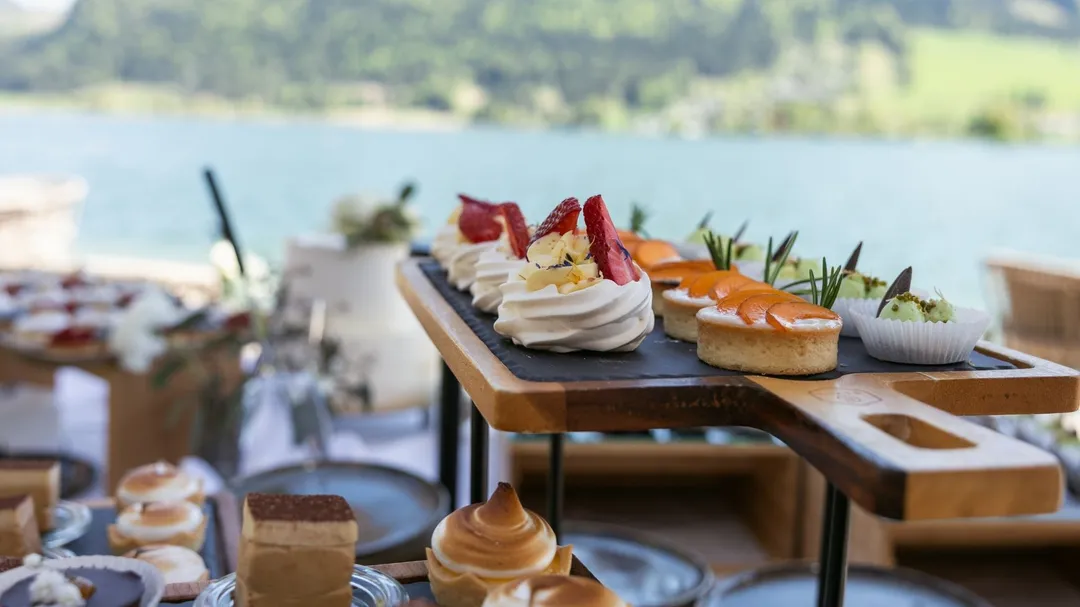 Dessert-Buffet mit Törtchen und Baiser auf Holzständer vor Seeblick