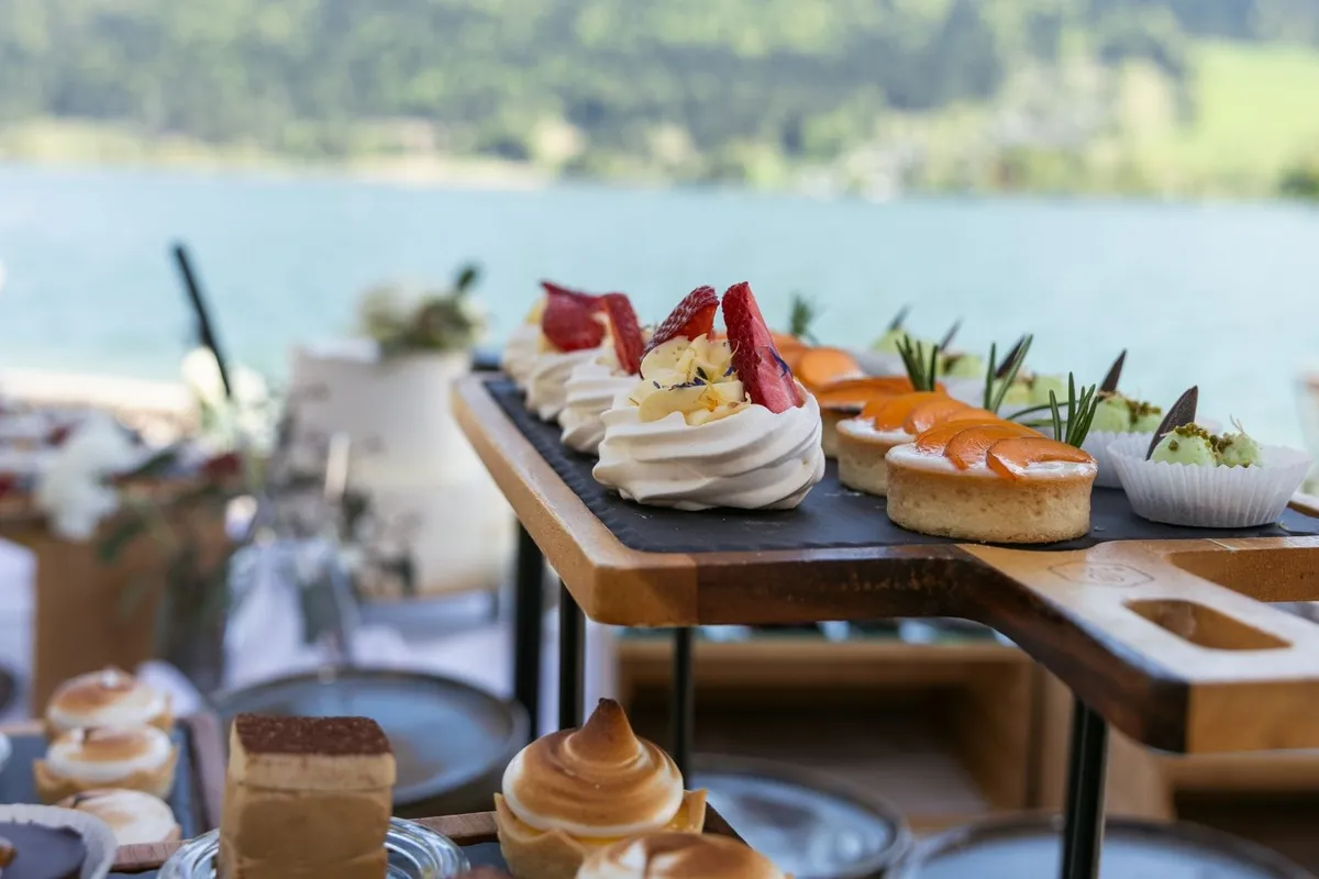 Dessert-Buffet mit Törtchen und Baiser auf Holzständer vor Seeblick