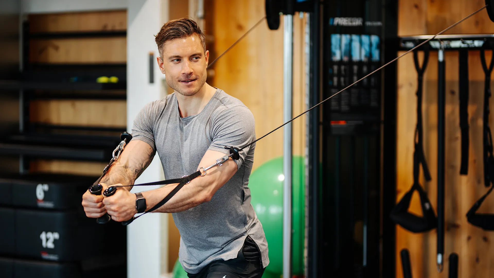 Mann trainiert an Kabelzug-Fitnessgerät im Fitnessraum