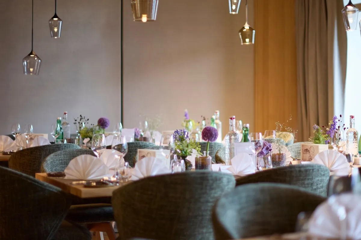 Gedeckte Tische im Restaurant mit Blumendeko und Stoffservietten