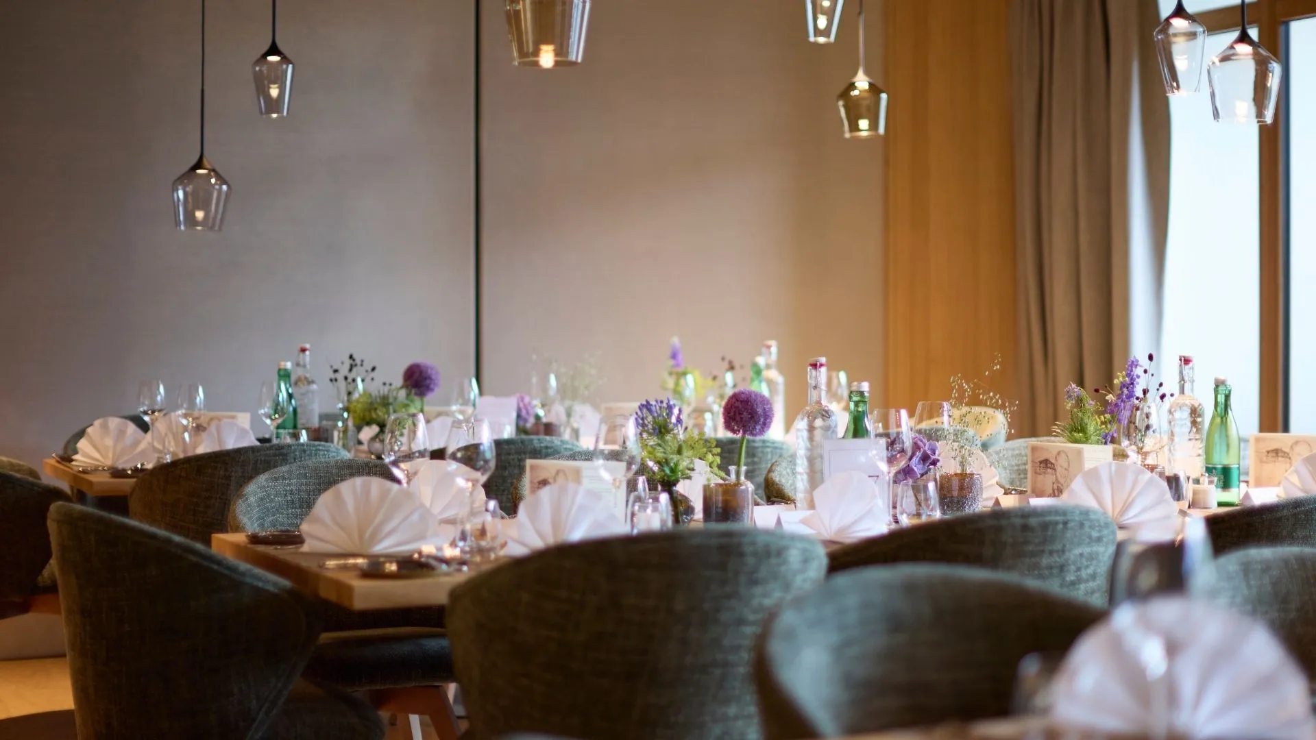 Gedeckte Tische im Restaurant mit Blumendeko und Stoffservietten