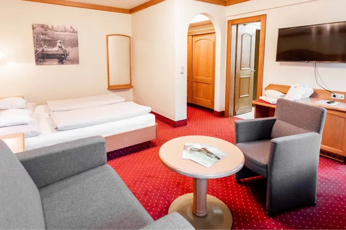 Hotelzimmer mit Doppelbett, Sitzecke und rotem Teppich