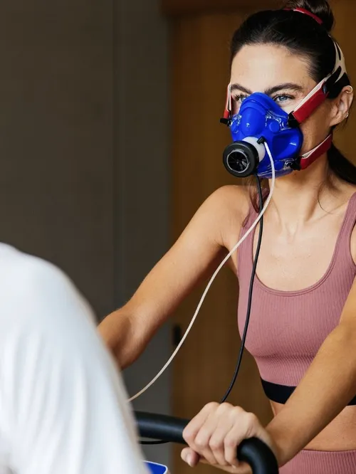 Frau mit Atemmaske bei Spiroergometrie-Test auf Trainingsgerät