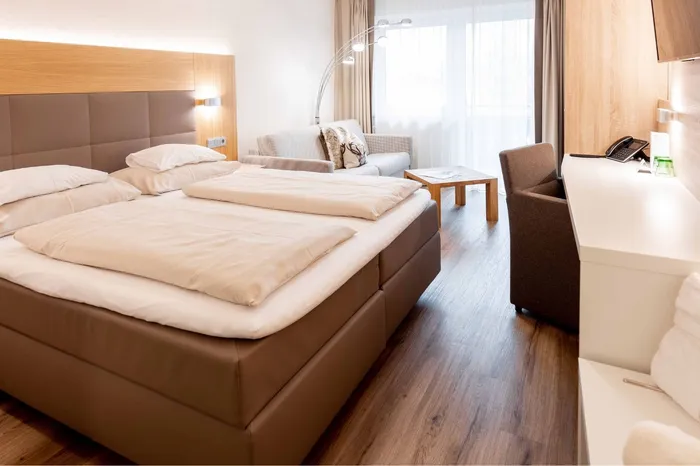Hotelzimmer mit Doppelbett, Sitzecke und Bademänteln
