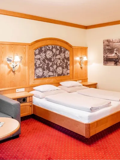 Hotelzimmer mit Doppelbett, Sitzecke und Holzvertäfelung