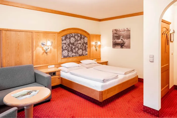 Hotelzimmer mit Doppelbett, Sitzecke und Holzvertäfelung