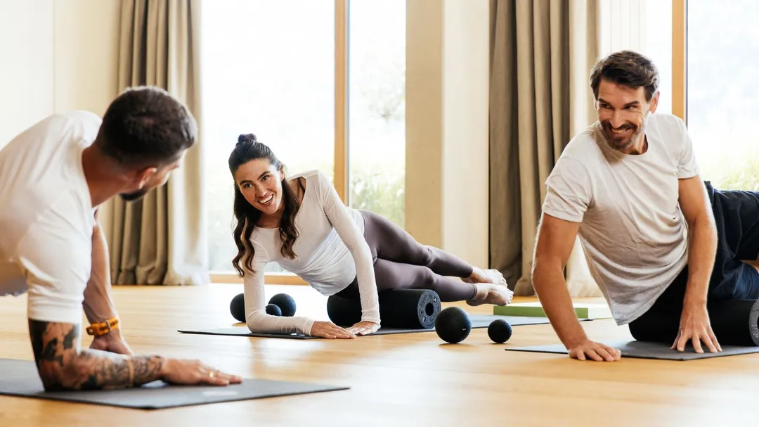 Gruppe trainiert mit Faszienrollen im Fitnessraum