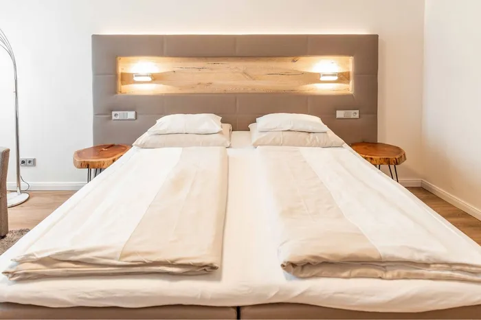 Doppelbett mit gepolstertem Kopfteil und Holzintarsie im Hotelzimmer