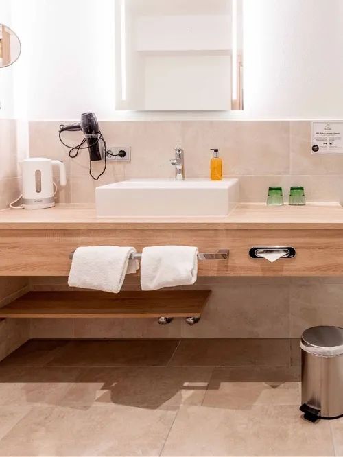 Modernes Hotelbadezimmer mit Waschtisch, Dusche und WC