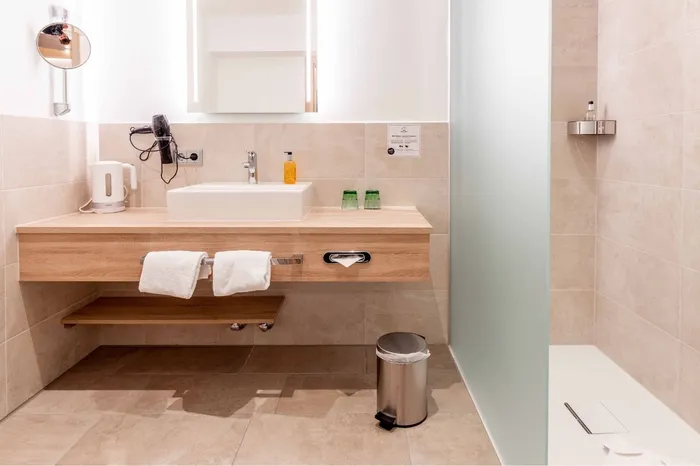 Modernes Hotelbadezimmer mit Waschtisch, Dusche und WC