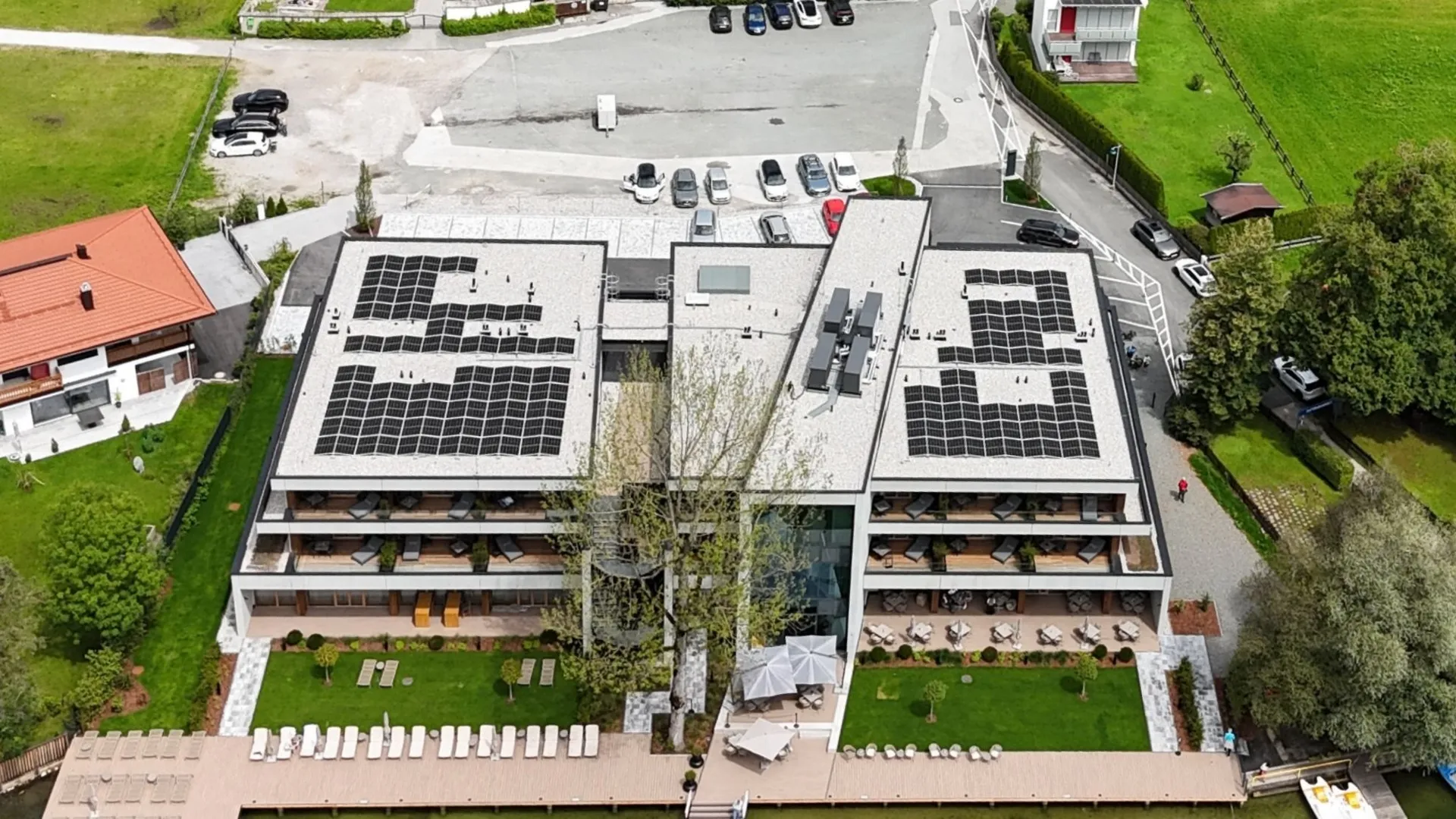 Luftaufnahme des Hotels mit Photovoltaikanlage auf dem Dach am See