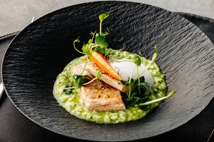 Lachsfilet auf grünem Risotto mit Karottenstreifen und Kresse