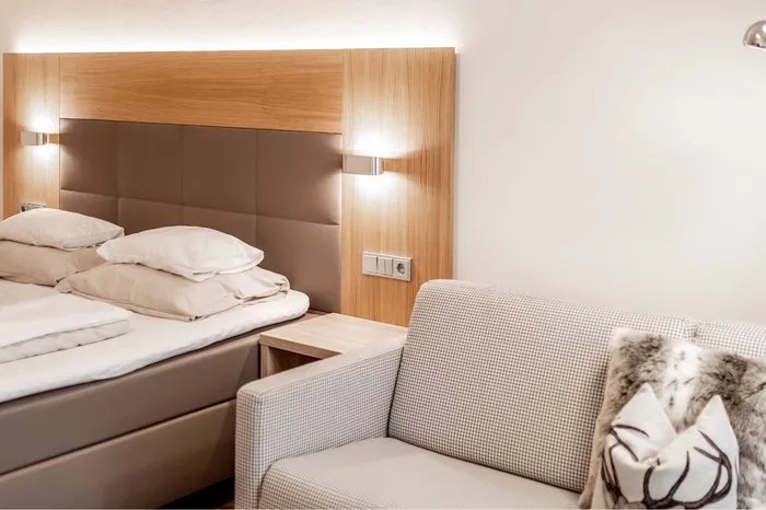 Hotelzimmer mit Doppelbett und Sitzcouch mit Kissen