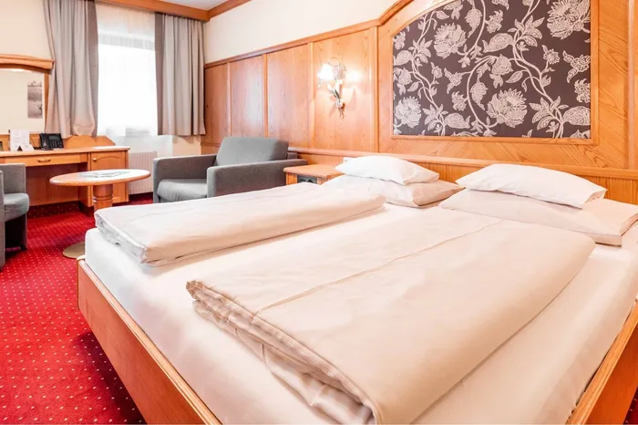 Hotelzimmer mit Doppelbett, Holzvertäfelung und rotem Teppich