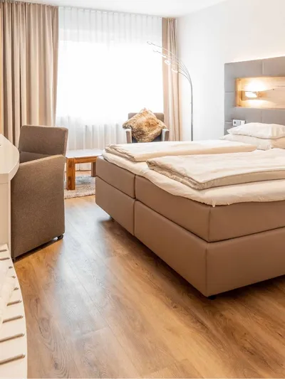 Doppelbett mit Kopfteil aus Holz und Leder in einem Hotelzimmer