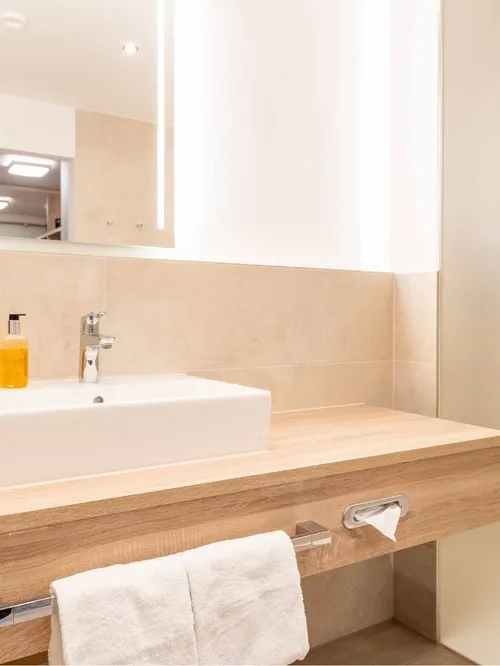 Waschtisch aus Holz mit Föhn, Spiegel und Handtüchern im Hotelbad