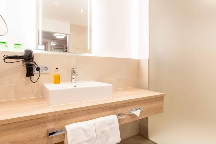 Waschtisch aus Holz mit Föhn, Spiegel und Handtüchern im Hotelbad