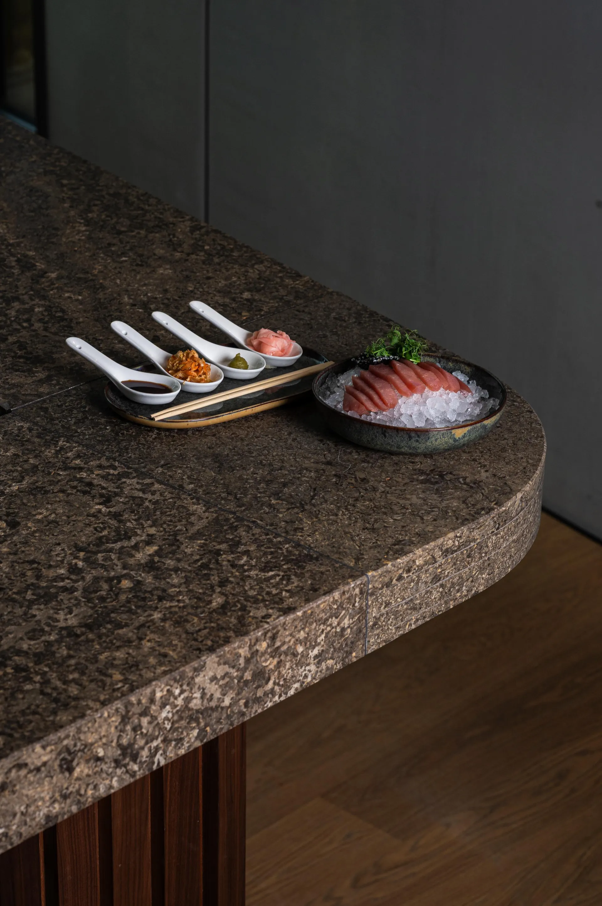Sashimi auf Eis mit Beilagen wie Ingwer und Wasabi auf Steintheke