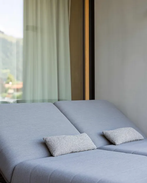 Betten mit blauem Bezug und Kissen vor Fenster mit Vorhang