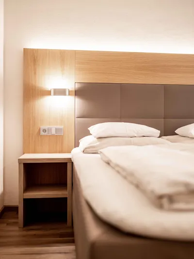 Bett mit Nachttisch und Wandleuchte im Hotelzimmer