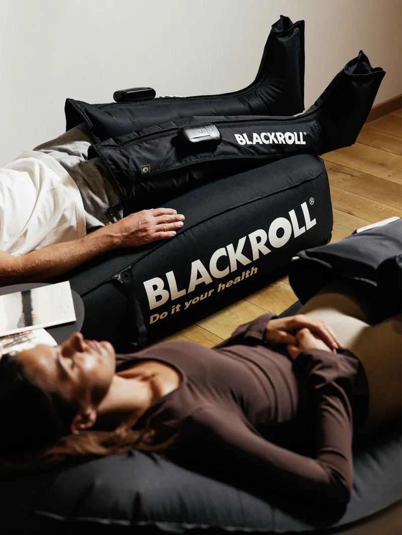Personen entspannen mit Blackroll-Kompressionsgeräten an den Beinen