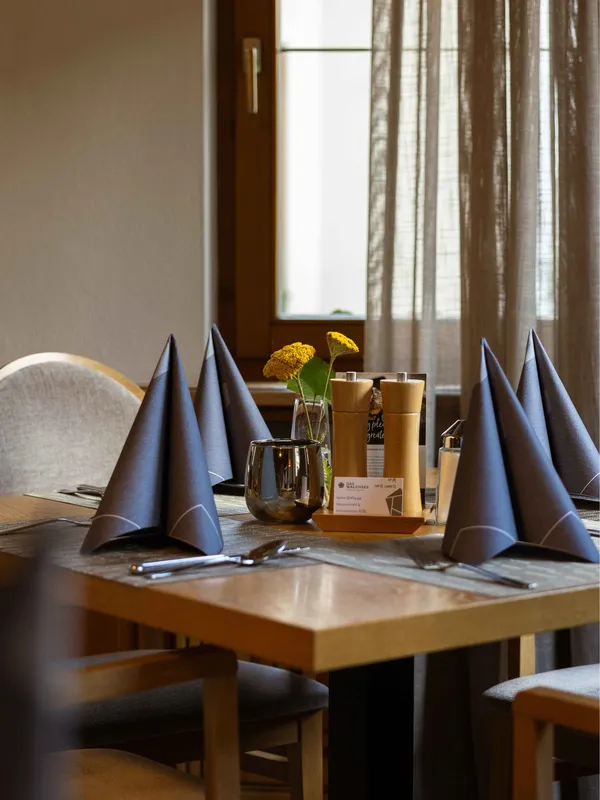 Gedeckter Restauranttisch mit gefalteten Servietten und Namenskärtchen im Hotel Walchsee