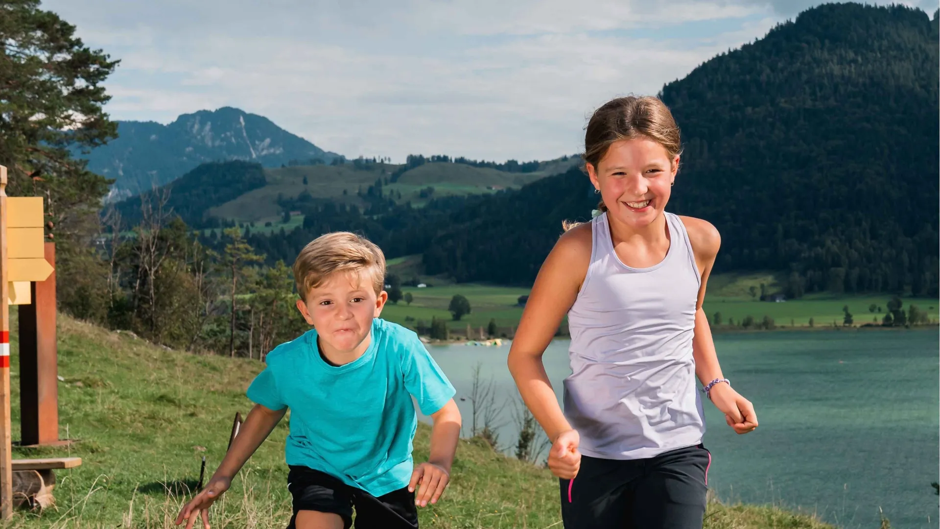 Zwei Kinder laufen über eine Wiese am Walchsee in Tirol