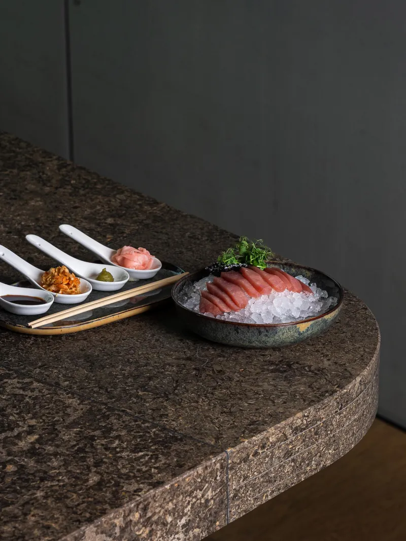 Thunfisch-Sashimi auf Eis mit Beilagen auf Steintheke