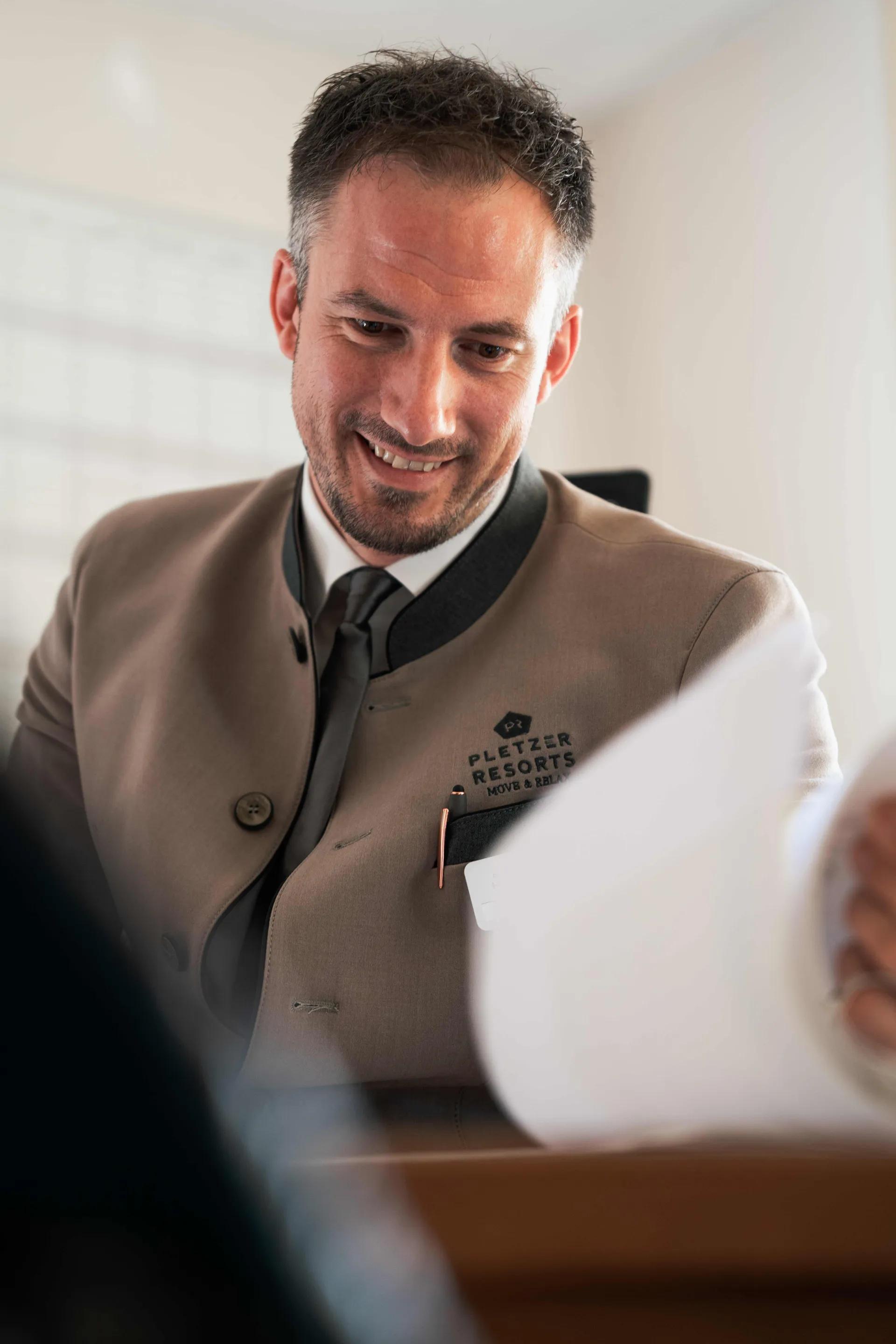 Lächelnder Mitarbeiter in Pletzer-Resorts-Uniform an der Rezeption