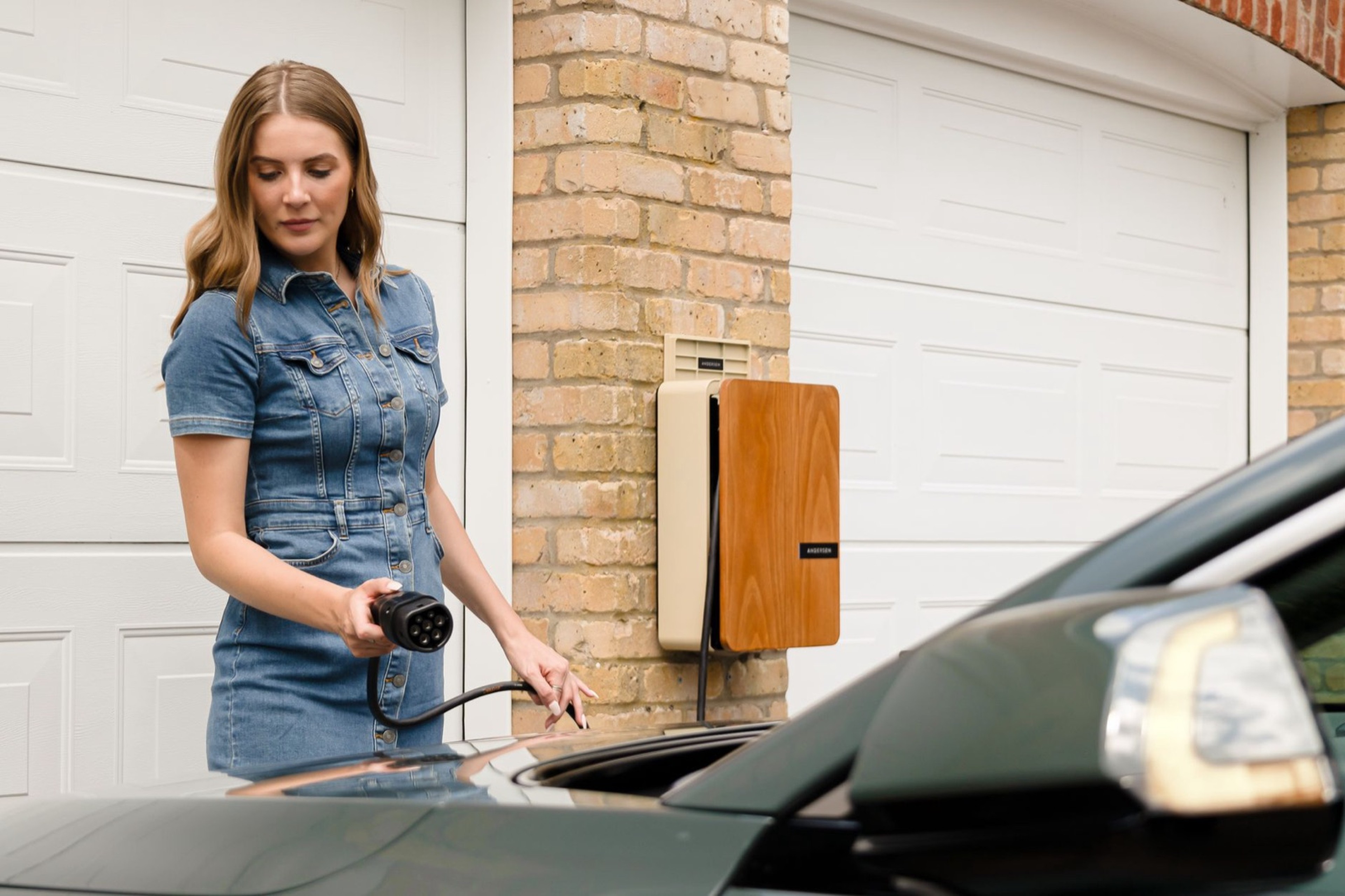 Femme branchant un chargeur de véhicule électrique à une station de recharge domestique