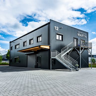 Zweigeschossige Flachdach-Lagerhalle mit integriertem Verwaltungsbereich, realisiert mit KS AT Wandpaneelen im Micro-Profil R9007 und X-Dek™ Flachdachsystem in 100 mm Stärke.