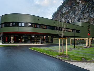 Grün verkleidetes, geschwungenes Firmengebäude vor Felswand, mit Kingspan Fassadenpaneelen