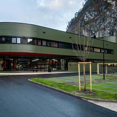 Grün verkleidetes, geschwungenes Firmengebäude vor Felswand, mit Kingspan Fassadenpaneelen