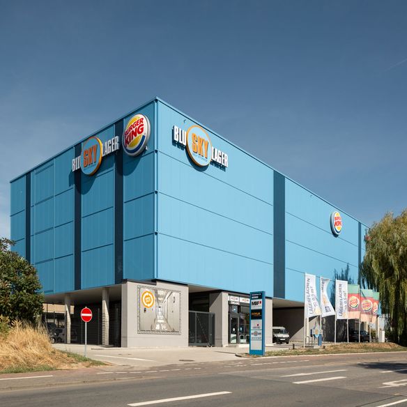 Ein echter Hingucker - die blaue Fassade passt zum Firmennamen. Bei Industriebauten macht auch die Gestaltung der Fassade durchaus Sinn. Auch wenn die Form funktional und zurückhaltend bleibt, können Farben Akzente setzen.
