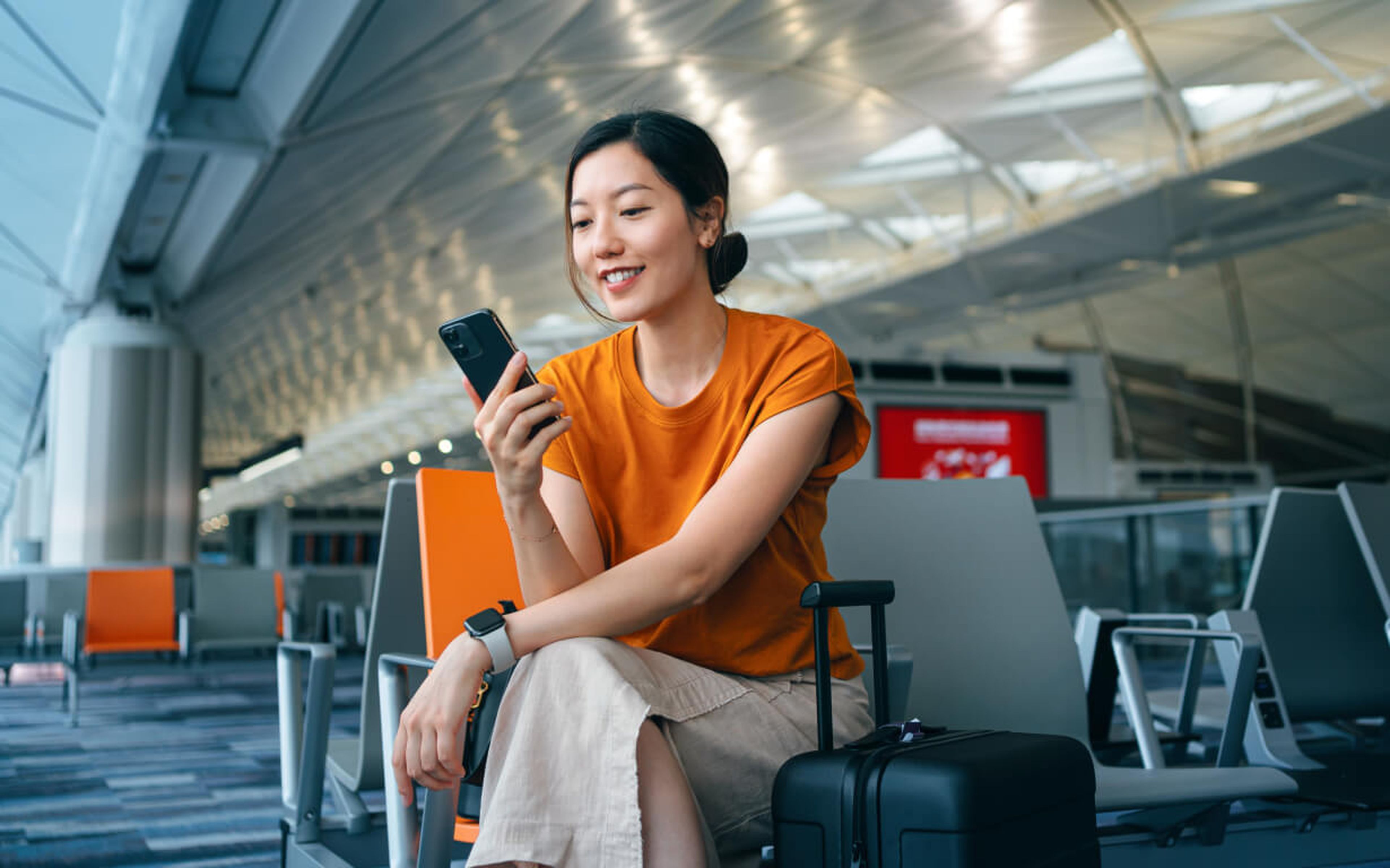 Asian woman looking at her phone in an airport.