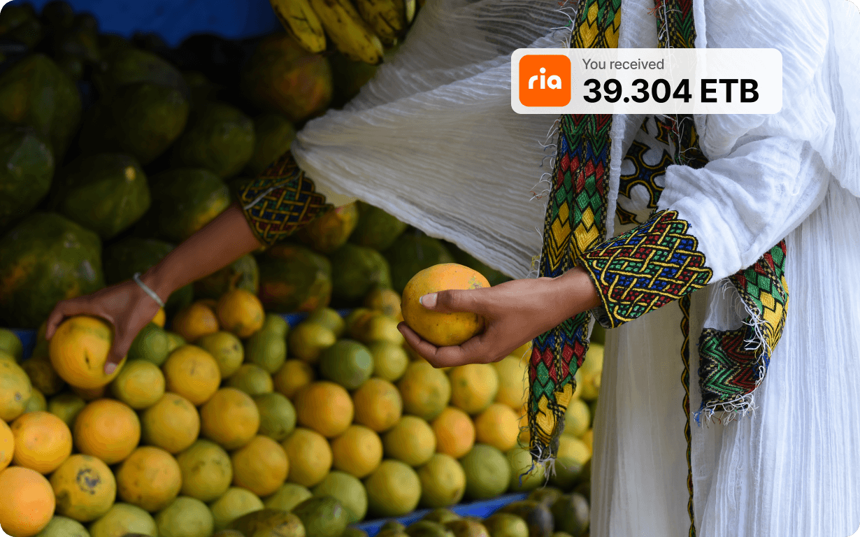 A person in traditional Ethiopian clothing selects mangoes at a fruit stand. An overlay shows a money transfer notification: "ria, You received 39.304 ETB.