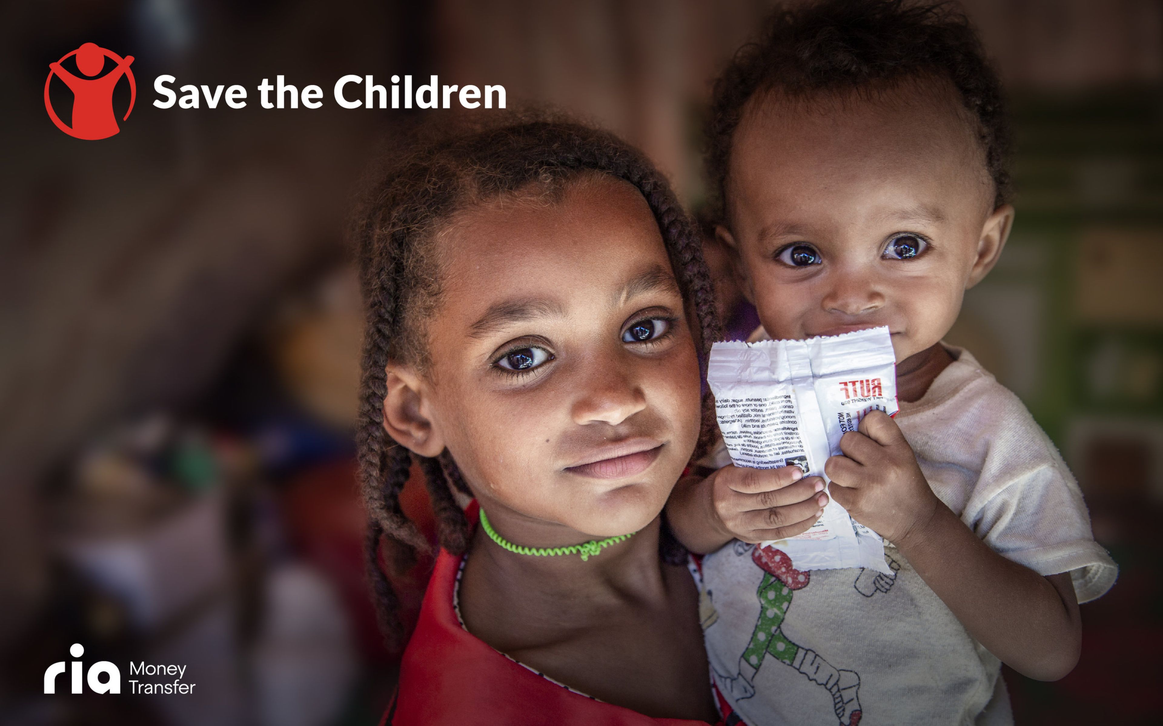 Two young children are depicted, with the older child on the left wearing a red shirt and the younger child on the right holding a food packet. The "Save the Children" logo is visible in the top-left corner, and "ria Money Transfer" is shown at the bottom-left.