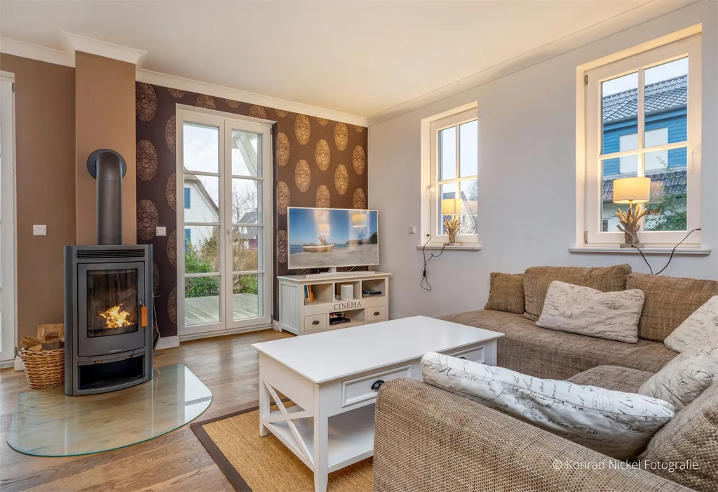 Heller Wohnbereich im Ferienhaus mit großen Fenstern, Holz und hellen Stoffen