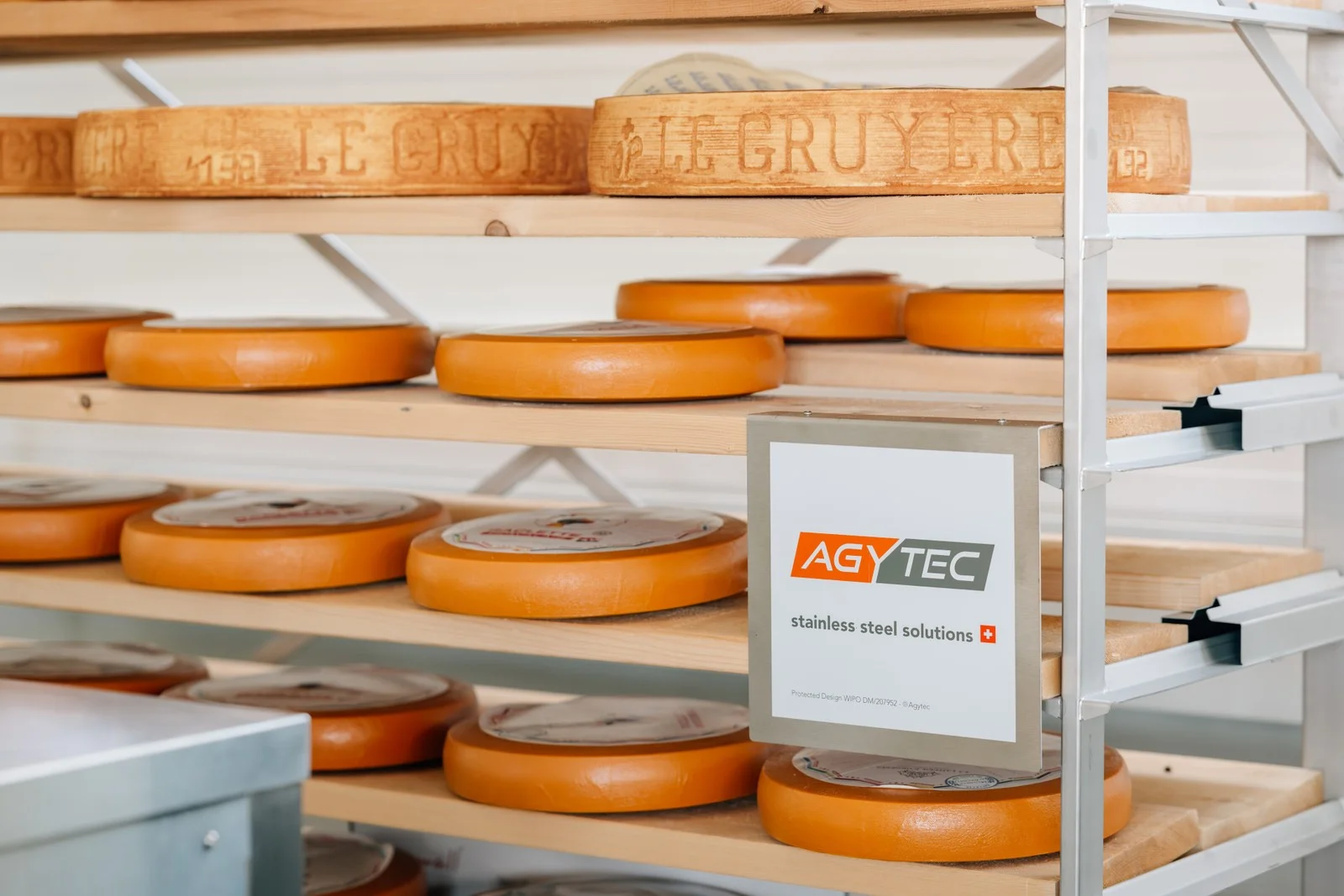 Reifungsregale mit Gruyere-Laiben und Agytec-Schild im Kaesekeller