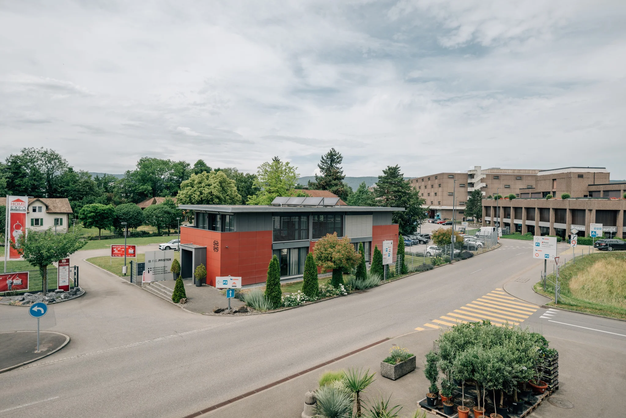 Firmensitz der F.G. Pfister mit rot verkleidetem Bürogebäude an der Strasse