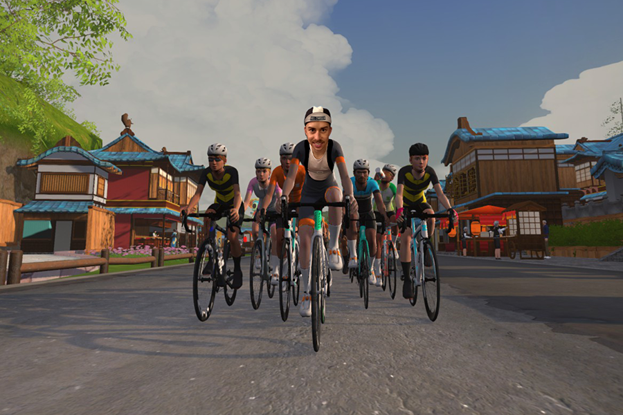 ZWIFT-Workouts von RaR und PBT A group of cyclists, led by an avatar with a real face, ride through a virtual Japanese-style village under a cloudy sky.