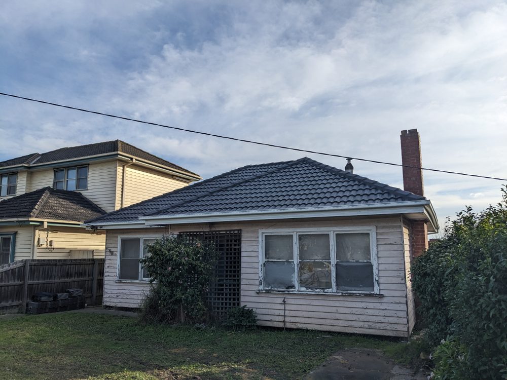 A Melbourne weatherboard home and its tiled roof under winter cloud