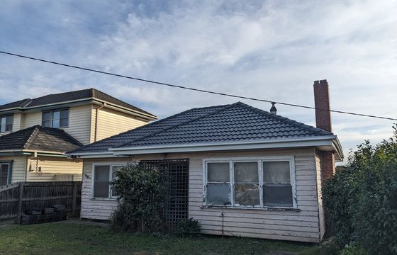A Melbourne weatherboard home and its tiled roof under winter cloud
