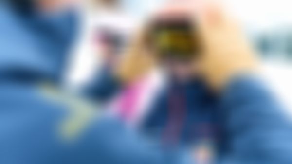 Ein Skilehrer setzt einem fröhlichen Kind sein Skibrille auf