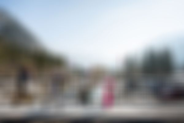 Eine Familie läuft mit Ihren Skiern hintereinander über eine Brücke